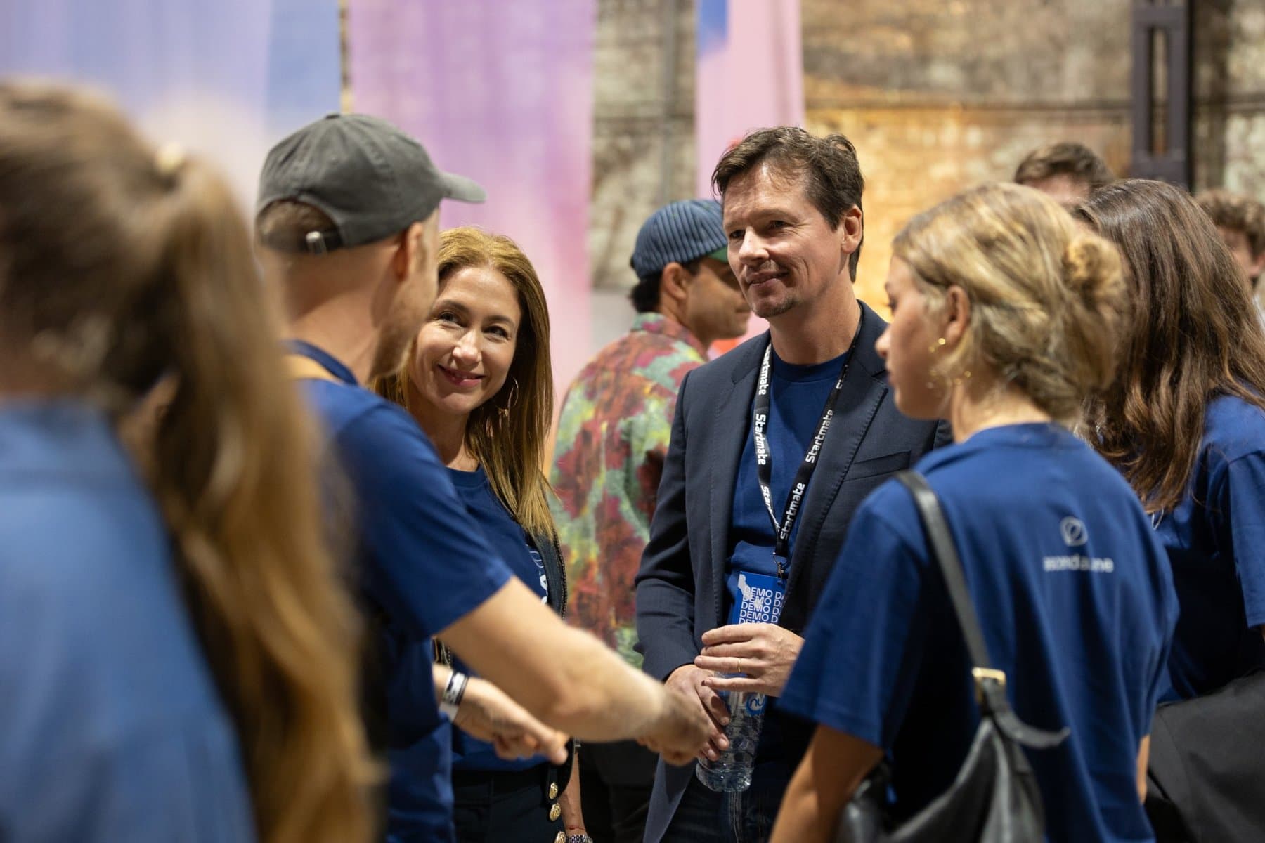 Nathan and Marisol Challen in team shirts, talking with founders at a Startmate Demo Day.